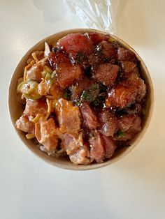 a bowl filled with meat and vegetables on top of a white tablecloth next to a plastic bag