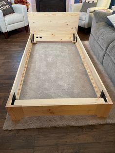 a wooden bed frame sitting on top of a hard wood floor next to a couch