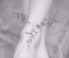 a woman's foot with flowers and leaves on the bottom part of her ankle