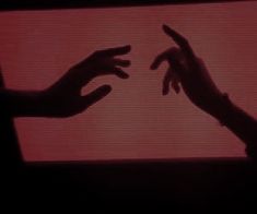 two hands reaching out towards each other in front of a red screen with the word love written on it