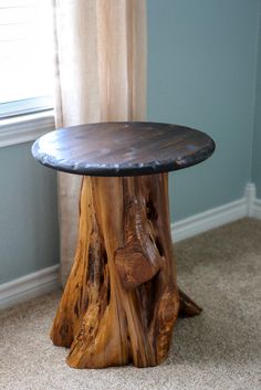 a table made out of tree trunks in a room with carpeted flooring and blue walls