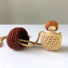 two small knitted dolls sitting next to each other on a white surface with rope