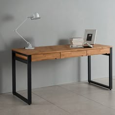 a laptop computer sitting on top of a wooden desk next to a lamp and books