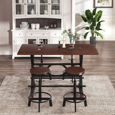 a dining room table with two stools and a potted plant