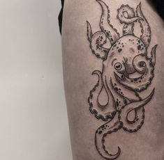 an octopus tattoo on the thigh is shown in black and grey ink, with intricate details