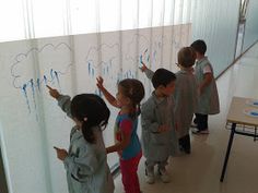 several children writing on a whiteboard in a room