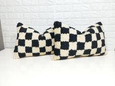 two black and white checkered pillows sitting on top of a table