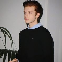 a young man standing in front of a plant