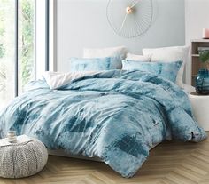 a bed with blue comforters and pillows in a room next to a window,