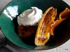 a green bowl filled with bananas and whipped cream