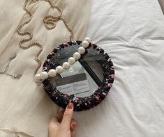 a person is holding a necklace on top of a bed with pearls and other jewelry