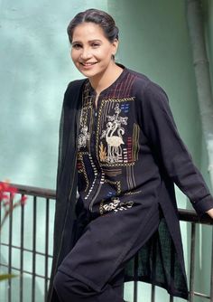 a woman standing on a balcony next to a metal railing and smiling at the camera