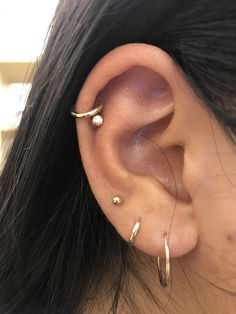 a woman's ear with two small gold hoops