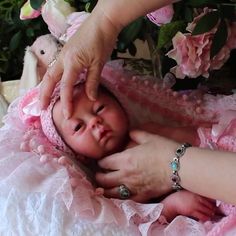 a baby is being held by a woman in a pink dress with flowers on it