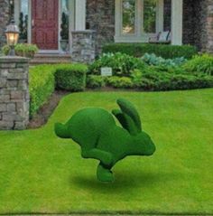 a green lawn with a house in the background and an animal made out of it