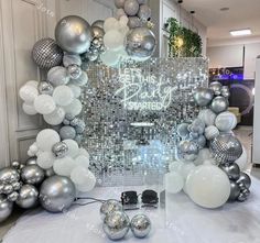 silver and white balloons are on display in front of a mirror wall with the words happy birthday