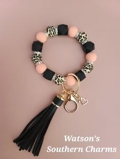 a black and pink bracelet with a tasseled keychain attached to it