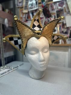 a white mannequin head wearing a gold and black crown on top of it