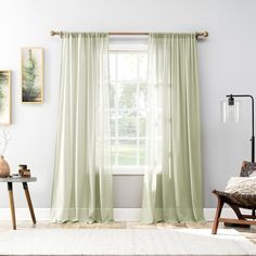 a living room filled with furniture and a window covered in light green drapes