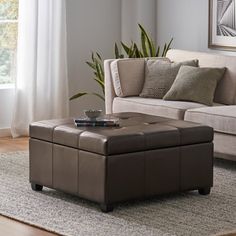 a living room with a couch, ottoman and coffee table in front of a window