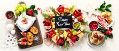 a table topped with lots of different types of fruit and pastries next to a chalkboard that says happy new year