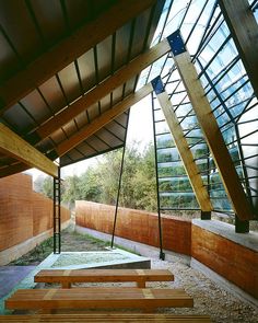 the inside of a building with wooden benches and glass windows on the roof, along with wood slats