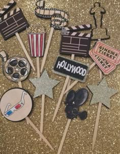 hollywood themed cupcake toppers on a gold glitter background with stars and clapsticks