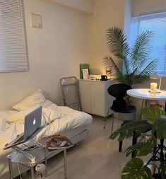 a bed room with a laptop on top of it next to a table and chairs