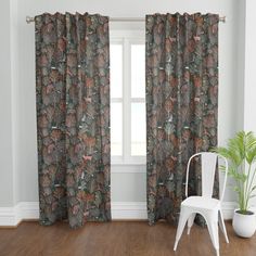 a white chair sitting next to a window in a room with wooden floors and curtains