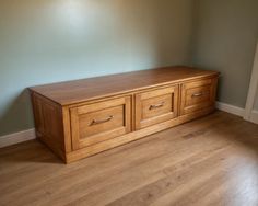 an empty room with a wooden bench in the corner and hard wood flooring on the other side