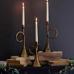 three candles are sitting on top of some books and one is holding a candle holder