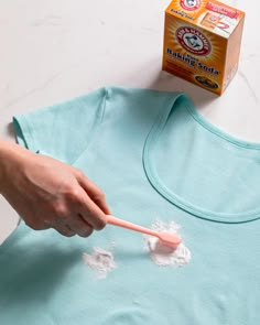 someone is using a toothbrush to clean their t - shirt with cotton floss