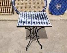 an outdoor table and chairs sitting next to each other in front of a wall with tile designs on it