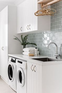 a washer and dryer in a white laundry room with green tiles on the wall