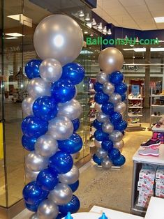 blue and silver balloons are hanging from the ceiling