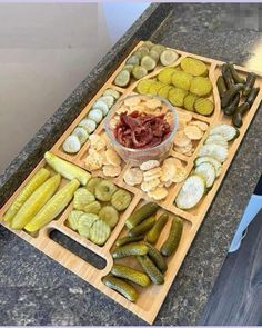 a wooden cutting board topped with pickles and crackers