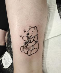 a small black and white tattoo of a teddy bear holding a honey jar