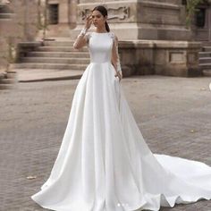 a woman in a white wedding dress standing on the street