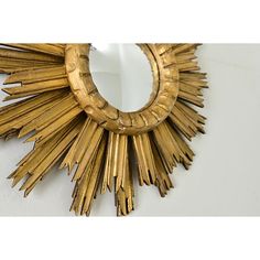 a gold sunburst shaped mirror hanging on a wall next to a white wall