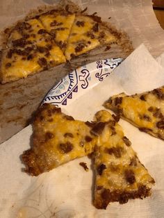 three pieces of pizza on top of a napkin next to a piece of blue and white paper