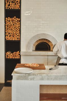 a man standing in front of a pizza oven