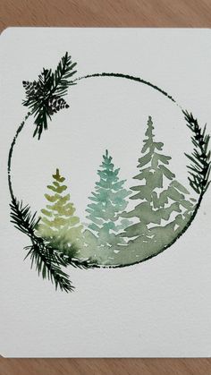 a watercolor painting of pine trees in a circle on white paper with green and blue ink