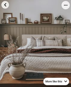 a bed with pillows and blankets on top of it next to a wooden shelf filled with pictures