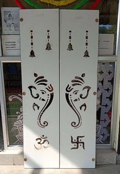 two white doors with designs on them in front of a store