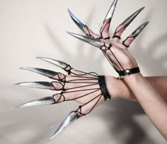 a person holding up their hands with multiple knives attached to the wrist and claws on each hand