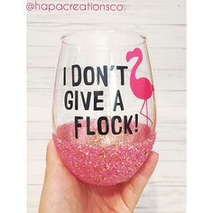 a hand holding up a wine glass with pink glitter in it and the words i don't give a flock