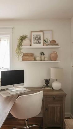 a desk with a computer on top of it next to a wall mounted shelf filled with pictures