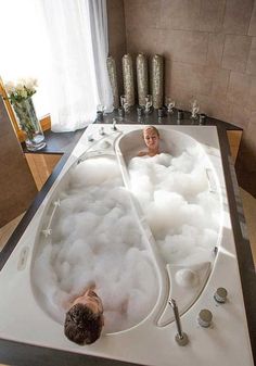 two people are in the bathtub with soapy water and bubbles on the floor