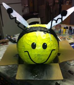 a paper mache bee sitting on top of a cardboard box