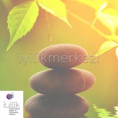 a stack of rocks sitting on top of a body of water next to green leaves